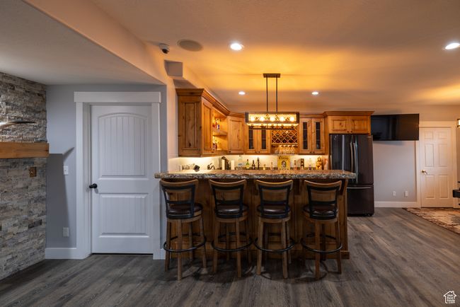 Indoor wet bar featuring freestanding refrigerator, dark wood-style flooring, pendant lighting, and recessed lighting | Image 50