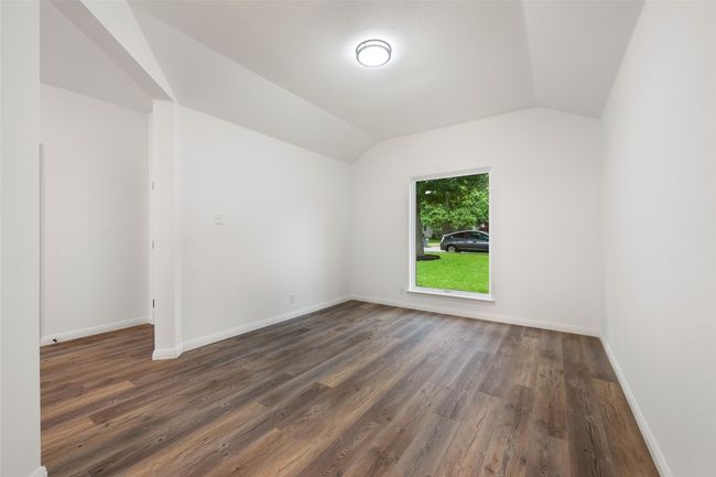 Unfurnished room featuring lofted ceiling and dark wood-style floors | Image 7