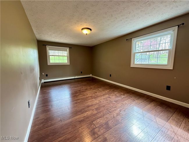Unfurnished room with a textured ceiling, baseboard heating, and dark wood finished floors | Image 31
