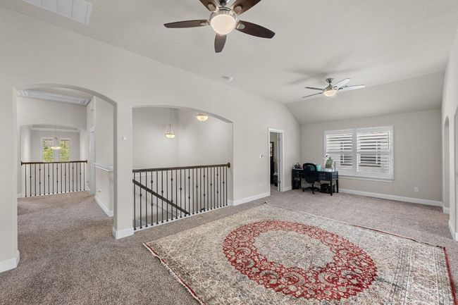 Game room with ceiling fan, carpet flooring, plenty of natural light, vaulted ceiling, and arched walkways | Image 26