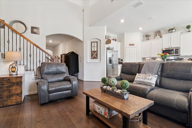 The open-concept design flows seamlessly into the welcoming family room, where hardwood floors, soaring ceilings, and a fireplace create an inviting atmosphere. | Image 8