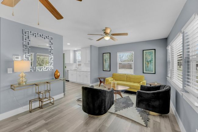 Living room with light wood finished floors, a healthy amount of sunlight, and a ceiling fan | Image 6