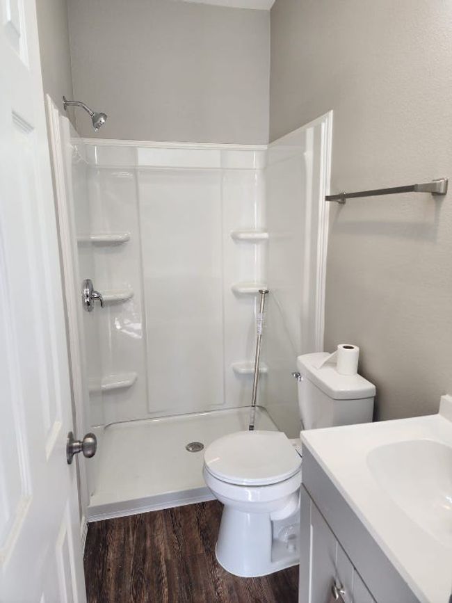 Full bath featuring wood finished floors, toilet, a shower, and vanity | Image 13