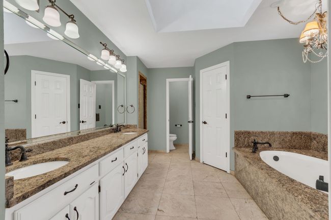 Bathroom featuring double vanity, a bath, tile patterned floors, and a chandelier | Image 18