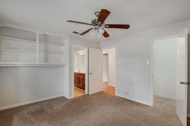 Unfurnished bedroom with carpet floors, baseboards, visible vents, and ensuite bathroom | Image 12