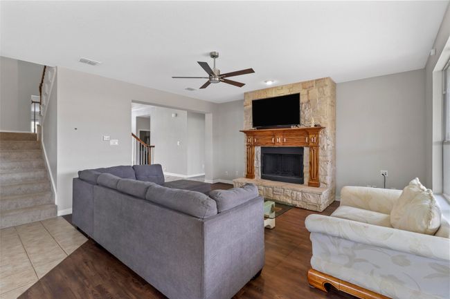 Living area featuring stairway, a ceiling fan, a stone fireplace, and wood finished floors | Image 13