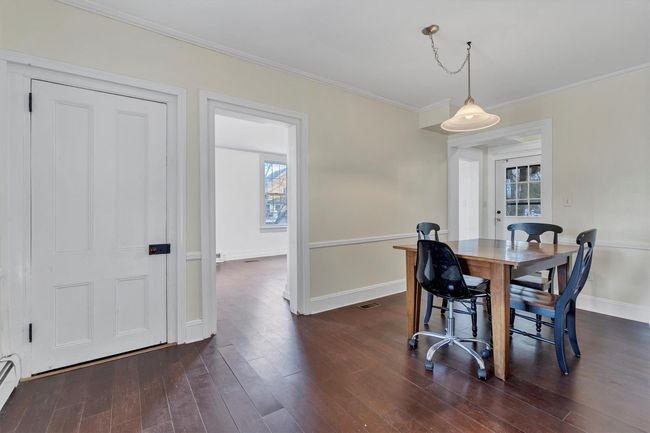Dining room with dark wood finished floors, ornamental molding, baseboard heating, and baseboards | Image 6