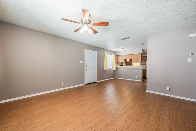 Unfurnished living room with a ceiling fan, wood finished floors, and a textured ceiling | Image 9