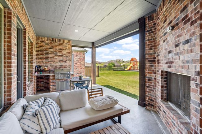 View of patio featuring grilling area, fence, an outdoor living space with a fireplace, and a playground | Image 35