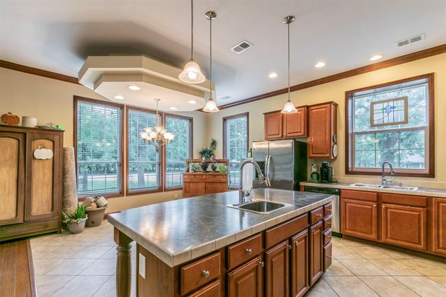 Kitchen featuring crown molding, a sink, appliances with stainless steel finishes, and brown cabinets | Image 6