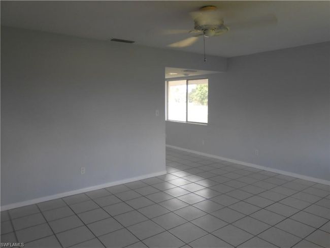 Empty room featuring a ceiling fan, visible vents, baseboards, and light tile patterned flooring | Image 4