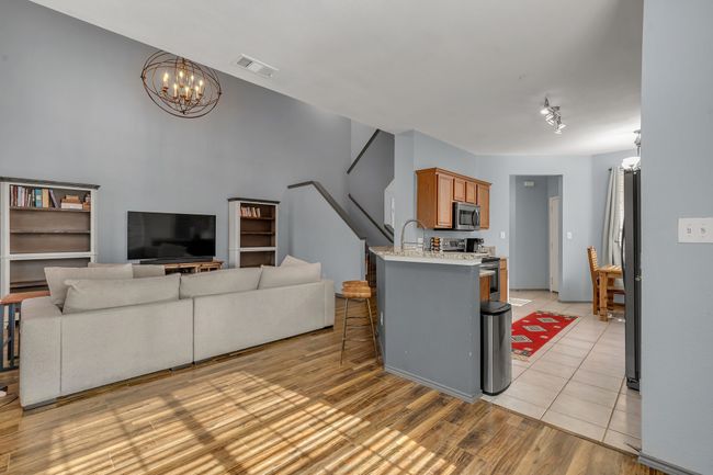 Kitchen with stainless steel appliances, a chandelier, a kitchen bar, and brown cabinetry | Image 12