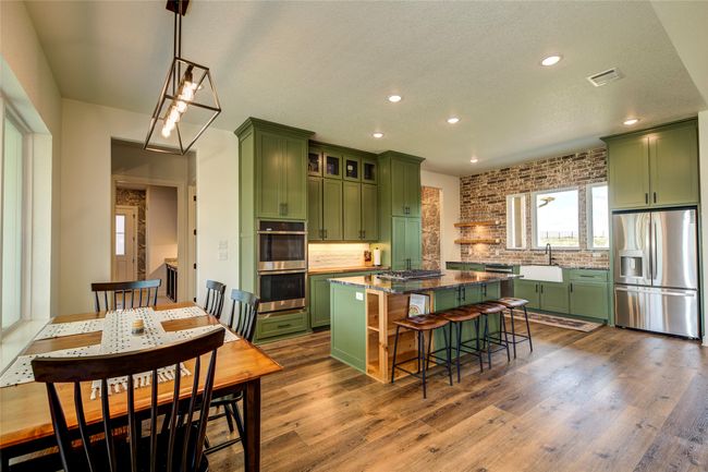 Kitchen with a kitchen island, stainless steel appliances, wood-type flooring, green cabinets, and a breakfast bar | Image 9