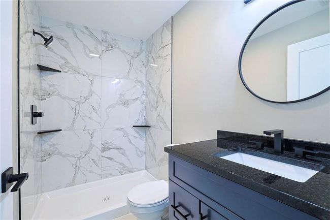 Bathroom with toilet, vanity, and tiled shower | Image 13