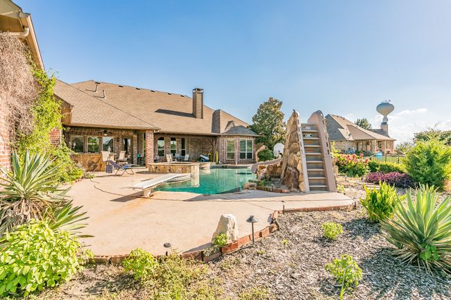 Swimming pool with a water slide, a patio area, a diving board, and stairs | Image 36