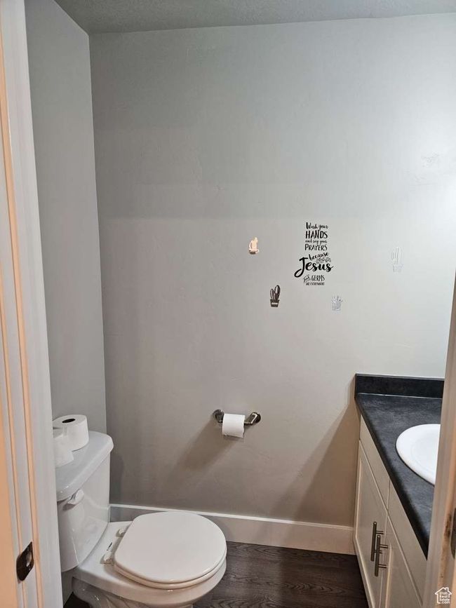 Half bathroom featuring toilet, wood finished floors, vanity, and baseboards | Image 7