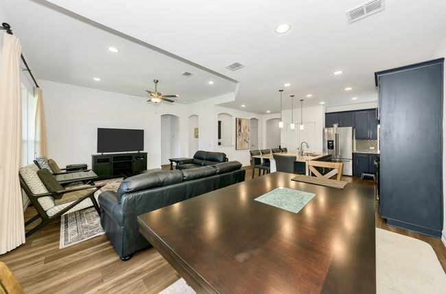 Living area with light wood finished floors, arched walkways, visible vents, recessed lighting, and ceiling fan | Image 10