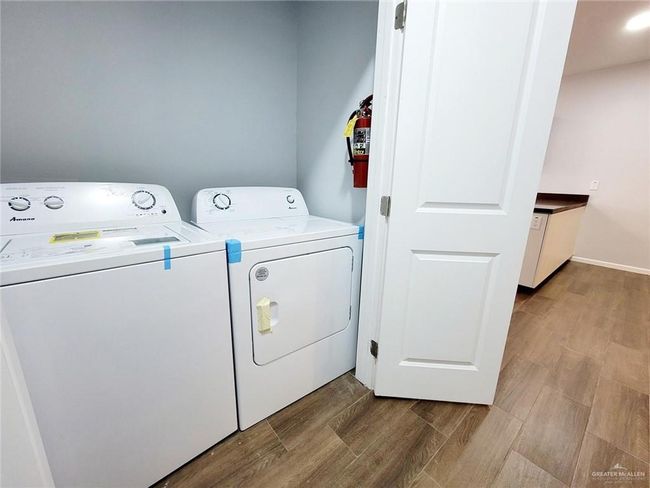 Clothes washing area with baseboards, laundry area, washing machine and clothes dryer, and wood finished floors | Image 19