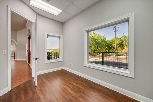 Unfurnished room with baseboards, dark wood-style floors, arched walkways, and a drop ceiling | Image 10