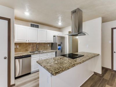 Kitchen featuring light stone countertops, appliances with stainless steel finishes, island exhaust hood, sink, and white cabinetry | Image 3