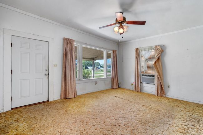 Unfurnished living room with cooling unit, baseboards, crown molding, and a ceiling fan | Image 5