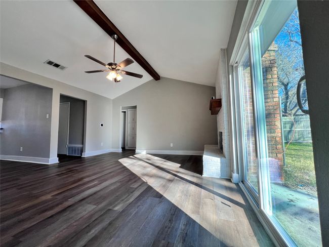 Empty room featuring ceiling fan, vaulted ceiling with beams, dark hardwood / wood-style floors, and a brick fireplace | Image 6