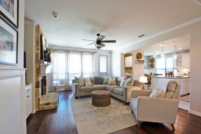 Living area featuring ceiling fan, dark wood-style floors, ornamental molding, and a healthy amount of sunlight | Image 16