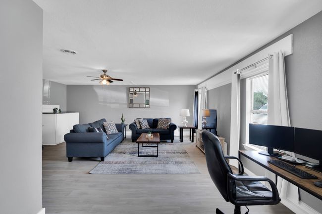 Living area with light wood finished floors, visible vents, and ceiling fan | Image 16