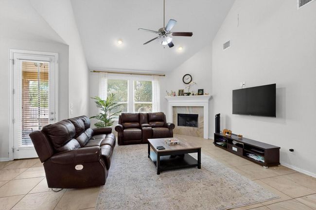Living area with a ceiling fan, arched walkways, a high ceiling, and light tile patterned floors | Image 5