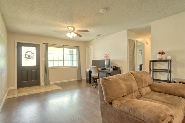 Living room featuring ceiling fan, a desk, a textured ceiling, and wood finished floors | Image 7
