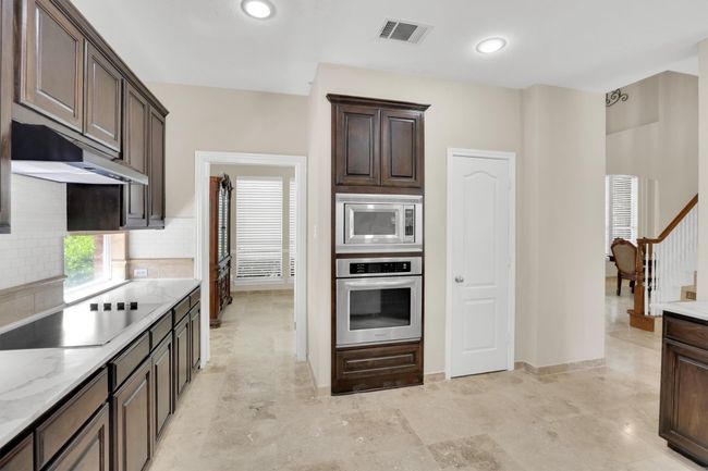 Kitchen featuring under cabinet range hood, visible vents, dark brown cabinetry, and stainless steel appliances | Image 14