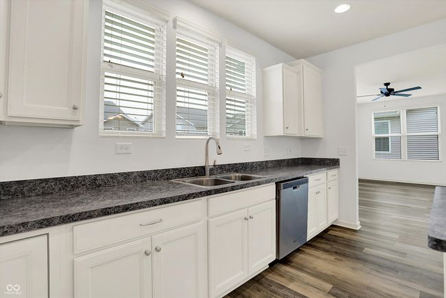 kitchen featuring dishwasher, dark countertops, ceiling fan, dark wood finished floors, and white cabinets | Image 7