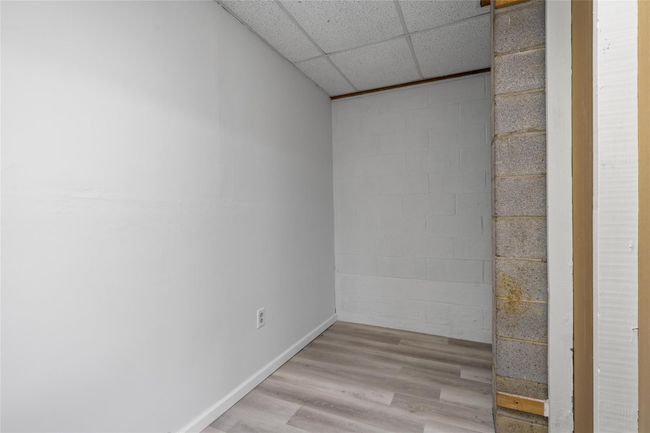 Unfurnished room featuring concrete block wall, a paneled ceiling, and light wood-style floors | Image 26