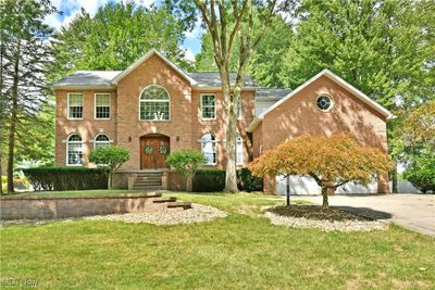 Colonial-style house with a front lawn and a garage | Image 1