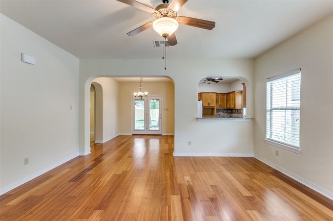 Unfurnished living room with a ceiling fan, arched walkways, light wood-type flooring, and a chandelier | Image 9