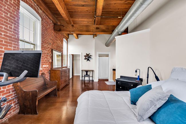 bedroom featuring beam ceiling, a towering ceiling, wood ceiling, and brick wall | Image 16