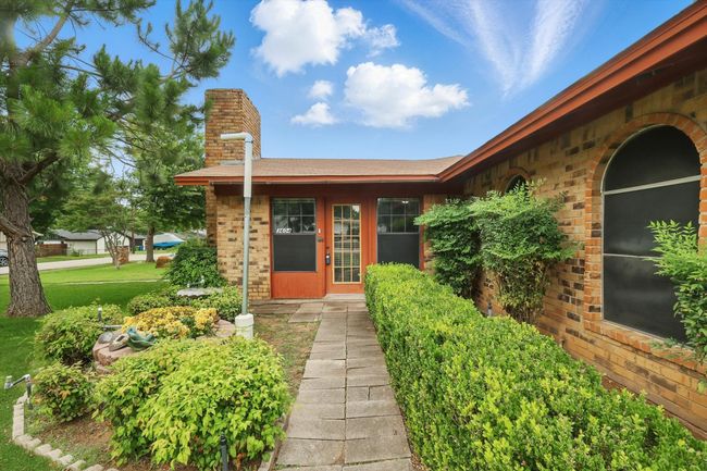 Doorway to property with a chimney, brick siding, and a yard | Image 6