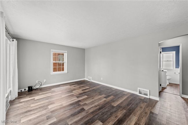 Unfurnished bedroom featuring dark wood-type flooring, visible vents, a textured ceiling, and baseboards | Image 8