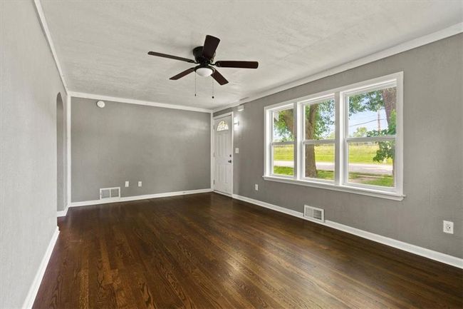 Unfurnished room with wood finished floors, ceiling fan, and arched walkways | Image 6