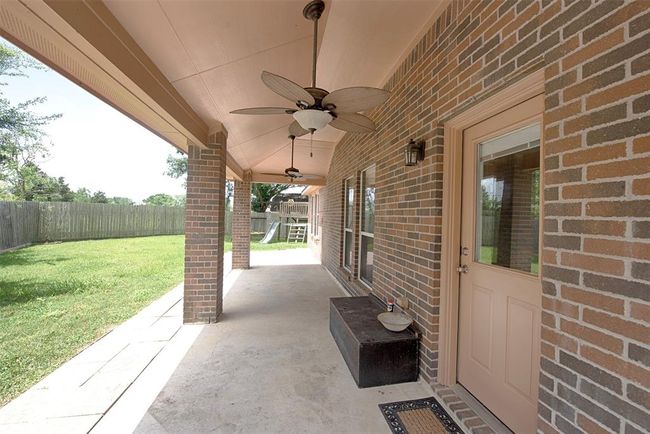 Out the back door is an amazing covered patio with two ceiling fans. Great spot for outdoor BBQ parties and dining. | Image 29