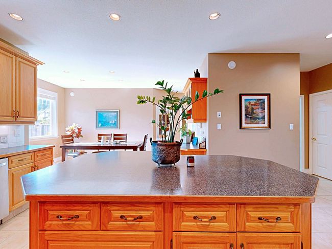 Kitchen featuring light tile patterned floors, a center island, recessed lighting, dishwashing machine, and dark countertops | Image 7