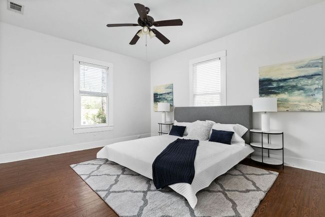 Bedroom with visible vents, multiple windows, baseboards, and wood finished floors | Image 14