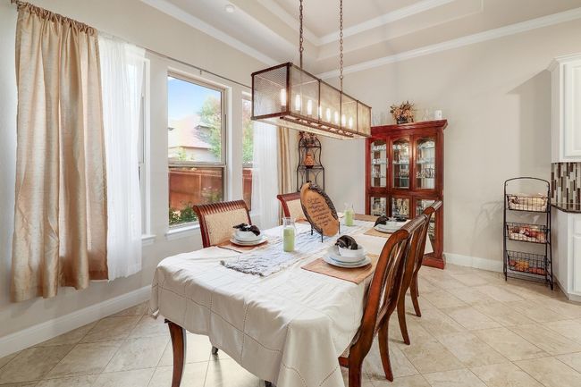 Dining area with light tile patterned flooring, ornamental molding, a raised ceiling, and a chandelier | Image 9