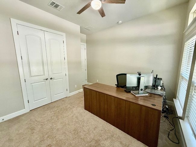 Carpeted home office with a ceiling fan and baseboards | Image 16