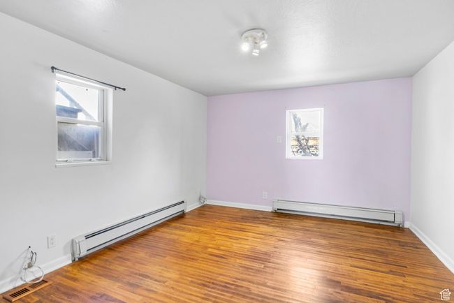 Spare room featuring baseboard heating, wood finished floors, and visible vents | Image 43