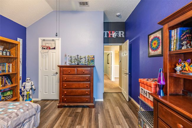 Bedroom with dark wood finished floors, baseboards, vaulted ceiling, and a textured ceiling | Image 29