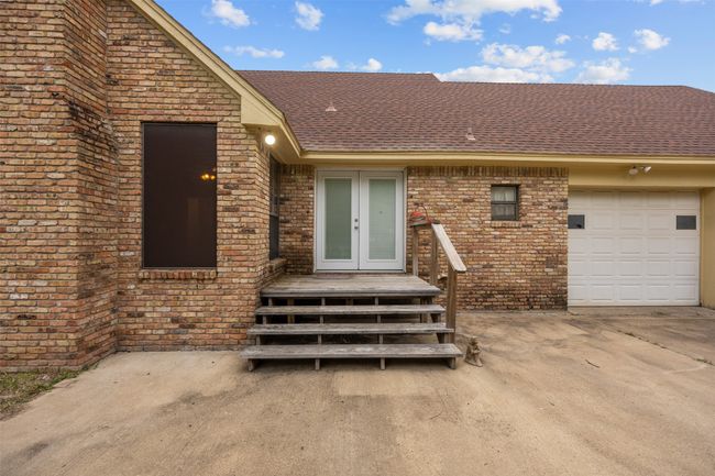 Property entrance with brick siding, french doors, a shingled roof, and an attached garage | Image 27
