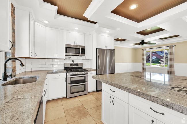 Kitchen with ornamental molding, appliances with stainless steel finishes, a sink, and white cabinets | Image 8