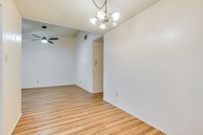 Empty room with light wood-style floors, a chandelier, and a ceiling fan | Image 8