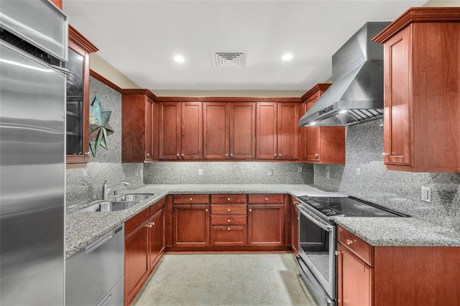 Kitchen features built-in refrigerator and commercial style exhaust vent hood. In 2023 the range and dishwasher were replaced. The dishwasher is a Fisher Paykel double drawer unit. Directly behind camera shot is Walk-In Pantry. | Image 17